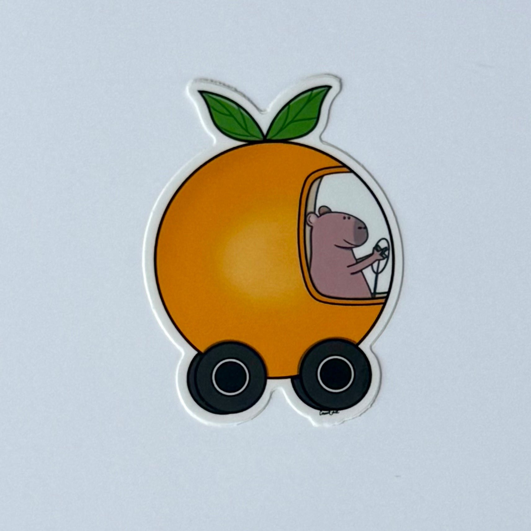 Capybara driving an orange car sticker