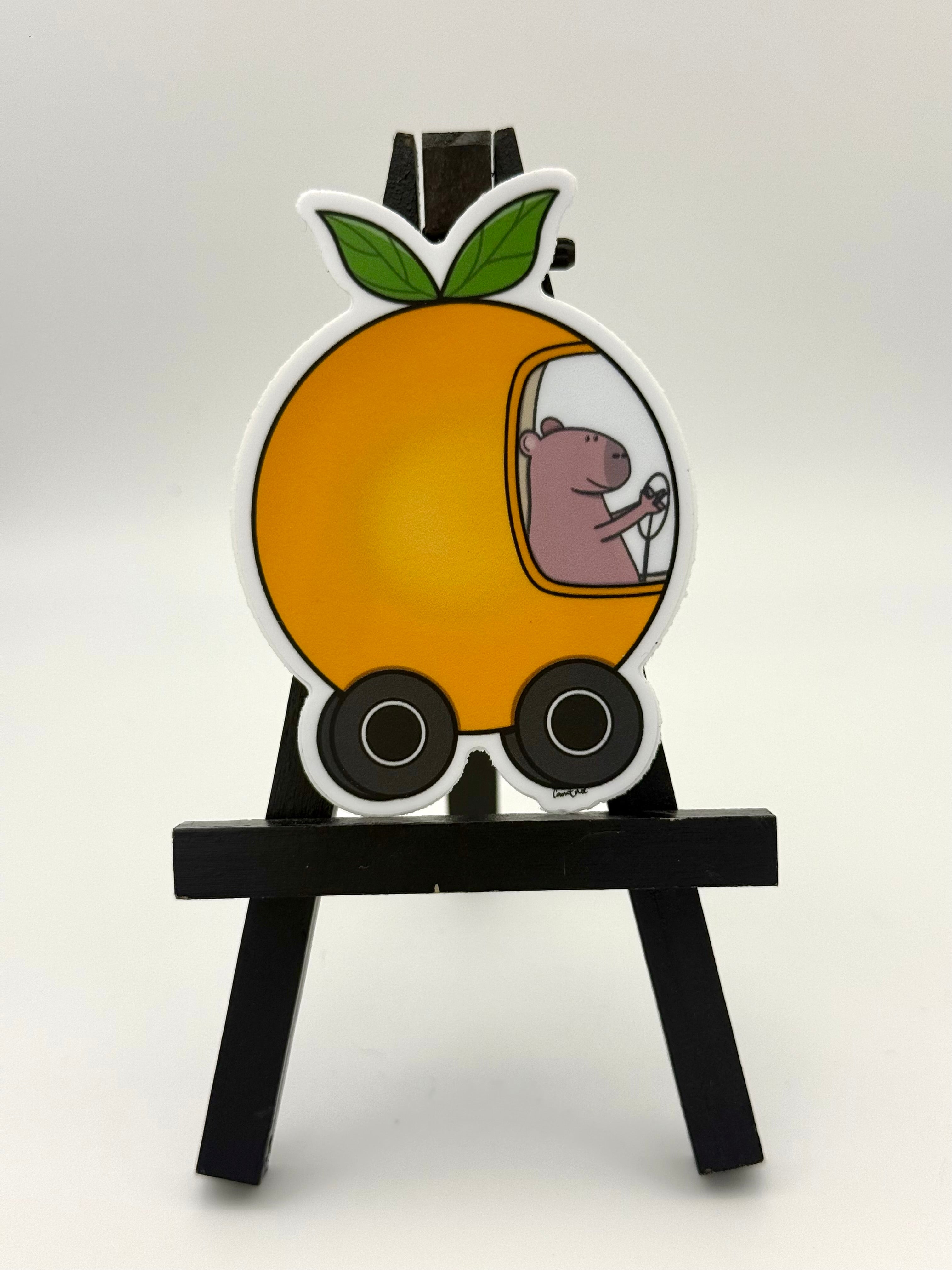 Capybara driving an orange car sticker