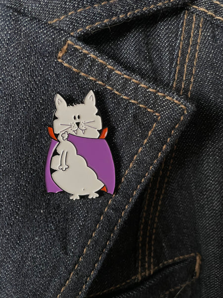 cat vampire enamel pin has a fat little cat in a vampire cape with two sharp pointy teeth pin is textured 