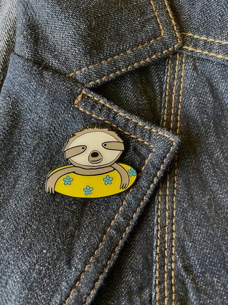 Sloth enamel pin- sweet sloth illustration in a yellow inner tube with blue flowers