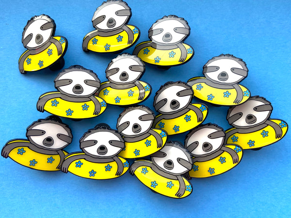 Sloth enamel pin- sweet sloth illustration in a yellow inner tube with blue flowers