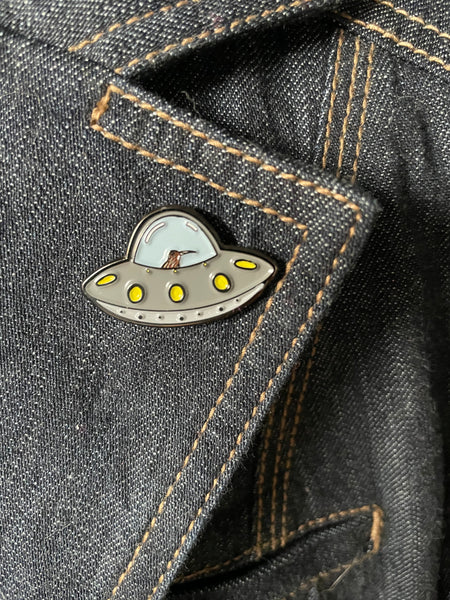 kiwi bird in a flying saucer enamel pin. small grey flying saucer with a kiwi at the helm- pin has texture and no resin coating