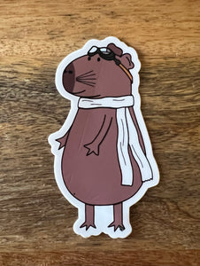 A capybara with goggles on top of his head and a long white scarf.
